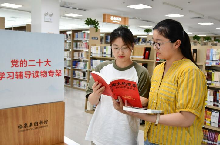 两名青年在党的二十大学习辅导读物专架前挑选喜爱的图书。赵怀勇摄